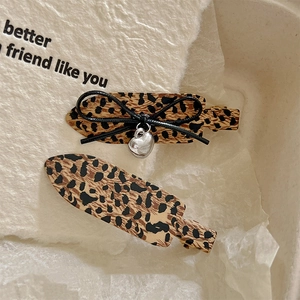Vintage leopard print bow hair clips with silver heart charms set on white background