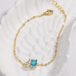 Détail macro d'une chaîne dorée avec zircon taille émeraude et pierre en forme de poire