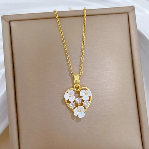 Macro shot of gold heart pendant with white flowers and zircons on white silk