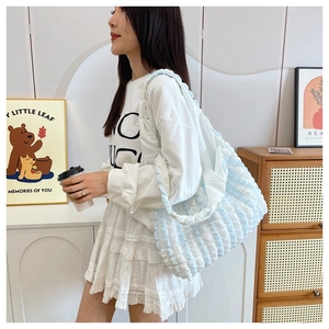 Lifestyle shot of light blue and white checkered pleated tote bag over the shoulder