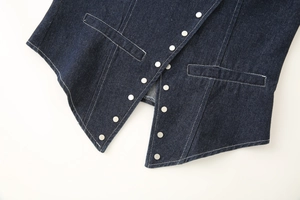 Macro detail of indigo denim vest showing silver metal buttons and white contrast stitching