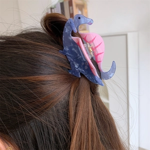 Detail view of cute dinosaur acrylic hair claw clips worn on long brown hair