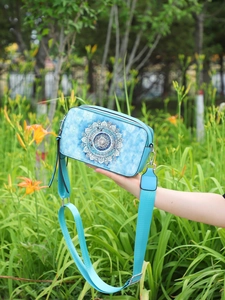 Detail of light blue crossbody bag with mandala print and adjustable shoulder strap