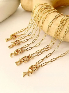 Detail of gold rectangular link necklaces with zircon initial pendants and ring clasps