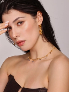 Detailed view of minimalist gold water drop earrings and multi-pendant bead necklace