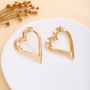 Detailed view of large gold heart earrings with flower pattern on a white tray
