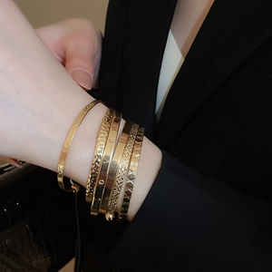 Detail of five-piece gold layered bracelets with LOVE engraving and floral patterns