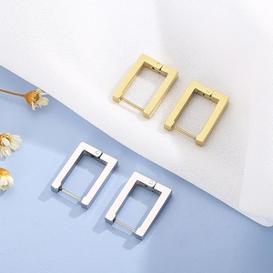 Detailed view of gold and silver rectangular geometric earrings on mesh fabric