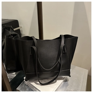 Dettaglio della borsa tote in pelle martellata nera su libri con riflesso specchiato
