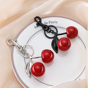 Close-up of glitter cherry keychains in red with silver and black metal leaf details