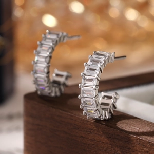 Macro detail of silver C-shaped earrings featuring rectangular baguette-cut cubic zirconia