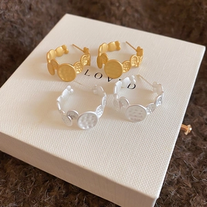 Detail of gold and silver C-shaped earrings with hammered metal texture on velvet