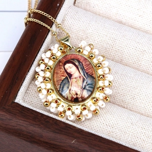 Close-up of Virgin Mary religious pendant with colorful beads in a wooden jewelry box