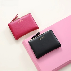 Close-up of minimalist women's short wallet with gold lettering and metal zipper detail