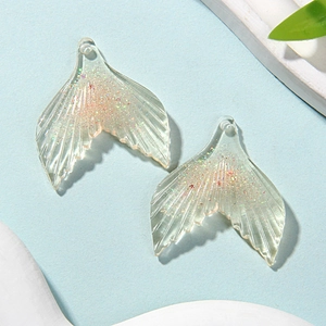 Detail of glittery resin mermaid tail pendants for DIY necklaces and crafts