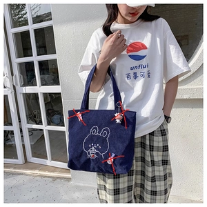 Detail of dark blue corduroy tote bag featuring a cute white cartoon rabbit illustration
