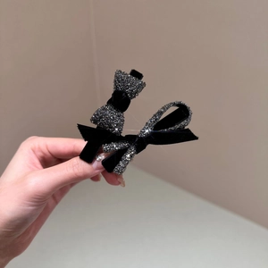 Close-up of black velvet bow hair clips featuring sparkling rhinestone detailing