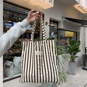 Detailed texture of black and white striped canvas tote bag with woven fabric logo patch