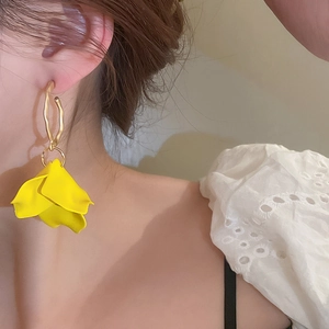 Close-up of a model wearing large yellow acrylic petal earrings with gold metal rings