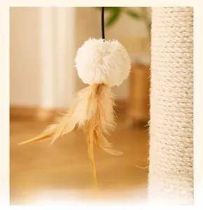 Detail of a cat scratcher toy featuring a plush white ball and natural feathers on a string
