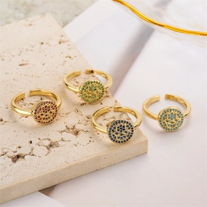 Detailed shot of four gold Fatima hand rings with colorful zircon on stone background