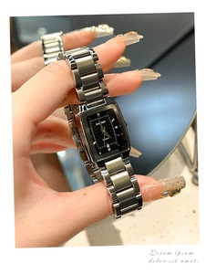 Detail of square silver quartz watch with black dial and date window on steel band