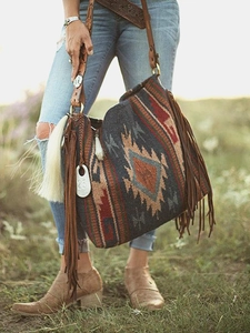 Close-up of bohemian woven tote featuring geometric patterns, long fringe and leather strap