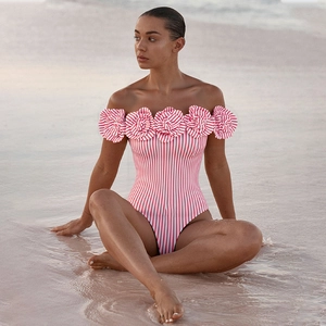 Detail des rot-weiß gestreiften Badeanzugs mit 3D-Blumenrüschen am rosa Strand