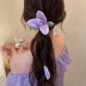 Detail of purple lily hair claw clip and matching floral hair tie set on a model