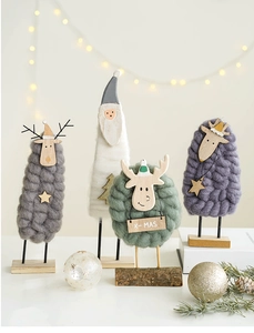 Macro detail of wool felt reindeer and Santa ornaments with wooden base and X-MAS tag