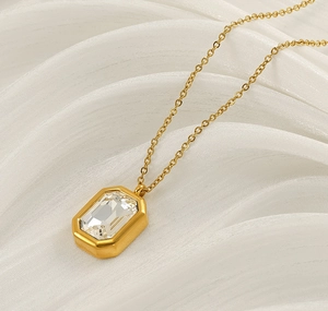 Detailed macro view of a step-cut rectangular crystal pendant on a gold chain