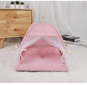 Pink floral pet tent with white lace curtains and pom-pom trim on a plush white rug