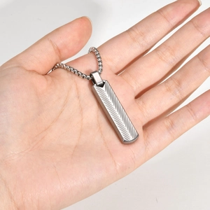 Detail of silver stainless steel geometric bar pendant with engraved chevron pattern