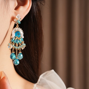 Primo piano di orecchino vintage con nappe di perle e gemme blu su una modella