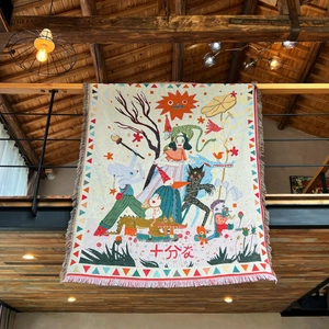 Close-up of Bohemian woven blanket with fringe details and whimsical folk illustrations