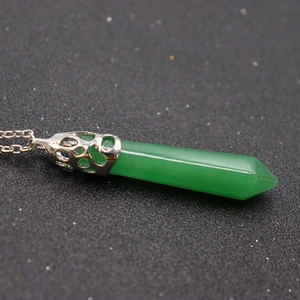 Macro shot of green hexagonal crystal pendant with silver hollow filigree and chain