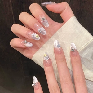 Detailed macro of pink almond nails with 3D flowers, butterfly charms, and cat-eye effect