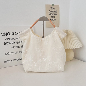 Detail of floral embroidery on cream canvas tote bag with woven rope handle