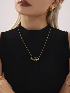 Détail du collier à pendentif épingle de sûreté dorée et créoles aux perles d'eau douce