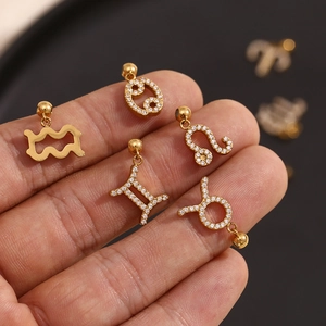 Detail of 18K gold plated zodiac pendants with crystals held between fingers