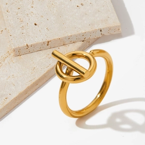 Close-up of minimalist gold OT-buckle stainless steel ring on beige travertine stone
