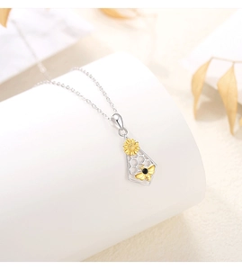 Detailed close-up of honeycomb pendant with golden sunflower and bee on silver necklace