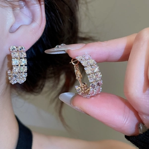 Macro shot of double-row cubic zirconia C-shaped hoop earrings with gold finish plating