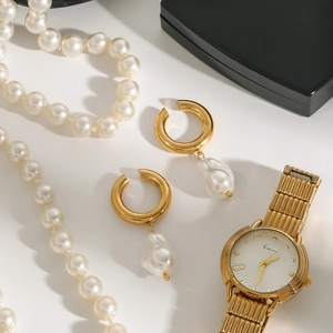 Détail de boucles d'oreilles dorées en C avec perles irrégulières et bijoux élégants