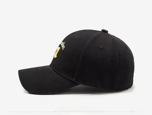 Side view of black corduroy baseball cap with yellow 3D letter embroidery and curved brim