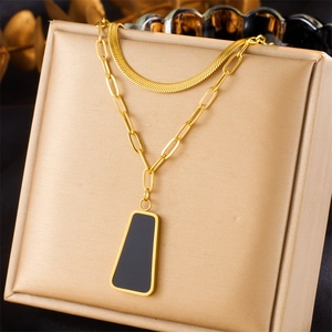 Detail of double-layer gold necklace with flat snake chain and black trapezoid pendant