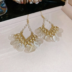 Detail of vintage gold earrings with fan-shaped shells and pearls in a jewelry box