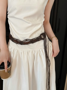 Detail of bohemian hand-woven brown waist belt with wooden beads and tassel accents