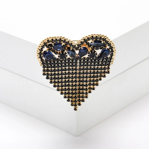 Detail of golden heart brooch with deep blue crystal teardrop and black rhinestones