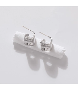 Macro detail of irregular silver geometric C-shape earrings with liquid metal texture